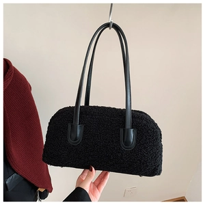 Detail of black faux shearling shoulder bag with sleek leather straps and minimalist texture