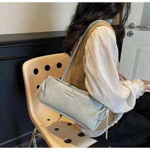 Close-up of light blue shoulder bag with drawstring side detail and metal logo plate