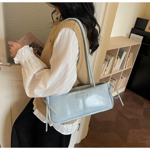 Detail of light blue minimalist Boston bag with decorative drawstrings and metal logo plate