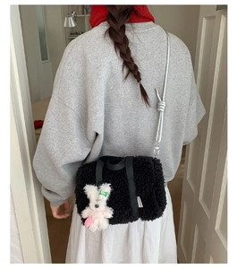 Detail view of black plush pillow bag with rabbit pendant worn over casual grey hoodie
