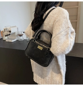 Detail of vintage black leather crossbody bag with gold hardware in a cozy lifestyle setting