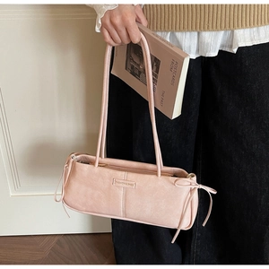 Detail of light pink baguette bag with decorative bows and metal zipper closure