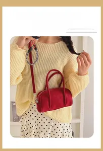 Close-up of a red vintage bowling handbag styled with a cozy cream knitted sweater