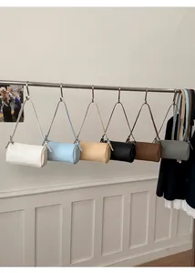 Minimalist barrel-shaped shoulder bags in six colors hanging from a metal rod