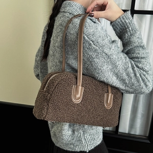 Close-up of brown faux shearling bag with coffee leather handles and metal feet