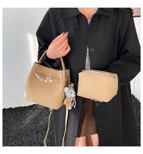 Detail view of khaki bucket bag with pebbled leather texture and cute blue bear charm