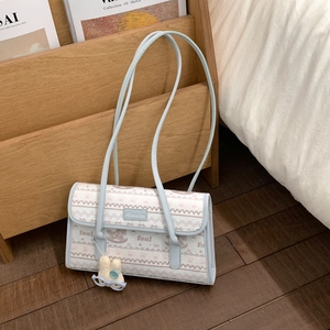 Detail of light blue striped shoulder bag with plush bunny charm and logo nameplate