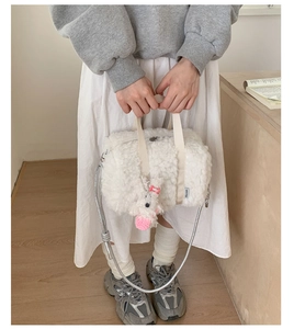 Close-up of white plush barrel bag with woven handle and cute puppy charm detail
