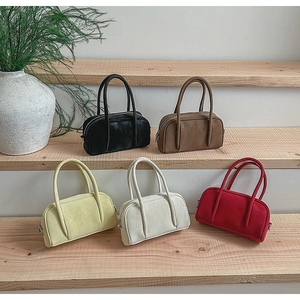 Minimalist bowling handbags in five vintage colors displayed on wooden stairs