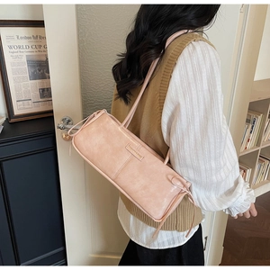 Detail of pink vintage bow baguette bag with adjustable shoulder strap and metal plate