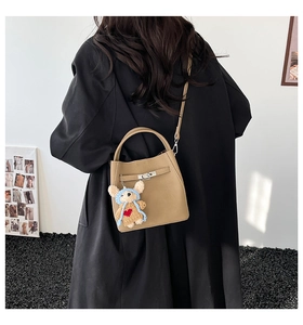 Brown bucket bag with cute bear charm shown on a person for daily casual style