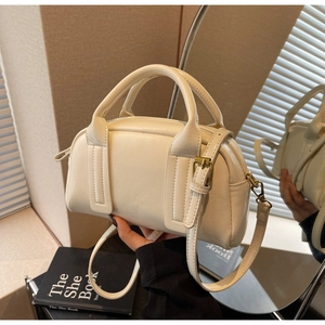 Gros plan du sac Boston crème en cuir grainé avec finitions métalliques dorées