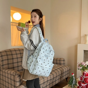 Detail of light blue floral backpack with side pocket and drawstring on female model