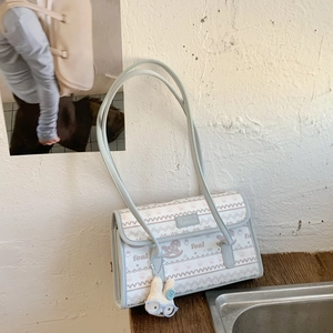Detail of mint green shoulder bag with animal patterns and a cute rabbit plush charm