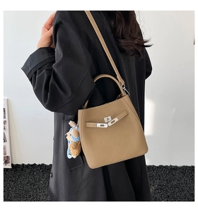 Detail of khaki bucket bag with lychee grain leather, metal twist lock, and bear charm