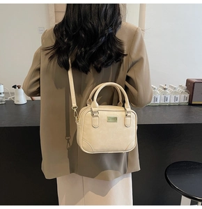 Detail of cream crossbody bag with soft leather texture and light gold metal plate