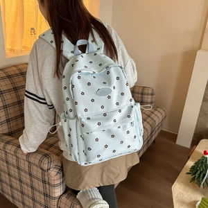 Close-up of light blue floral backpack with side pockets and smooth zipper details