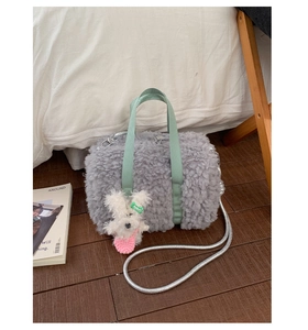 Detail of grey plush bucket bag with green handles and white puppy charm accessory