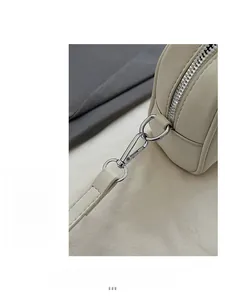 Detailed macro view of silver metal hook and leather strap attachment on beige handbag