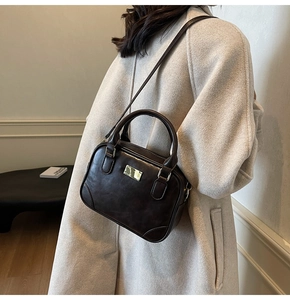 Close-up of vintage brown leather crossbody bag with gold metal plaque and stitching