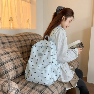 Detail of light blue floral canvas backpack with Fashion logo worn by a student