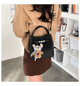 Detail view of black pebble leather bucket bag with silver twist lock and bear charm
