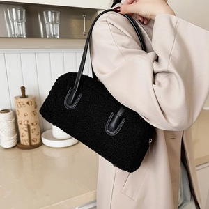 Close-up of black fuzzy fabric texture and leather strap on stylish underarm bag