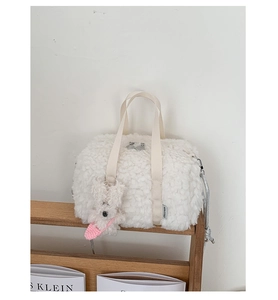 Close-up of white plush fleece pillow bag with cute puppy charm and silver zipper detail