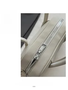 Detail of silver metal zipper and textured lychee pattern on beige PU leather bag