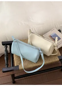 Detail of light blue and cream cylindrical crossbody bags in premium lychee leather