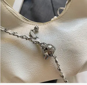 Gros plan du sac en cuir blanc plissé avec bandoulière à chaîne et boule argentée