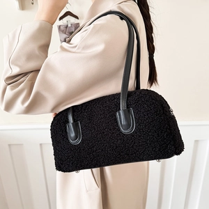 Close-up of black faux shearling shoulder bag featuring leather straps and fuzzy texture