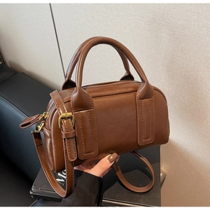 Vue détaillée du sac Boston marron avec texture cuir brillant et zip doré élégant
