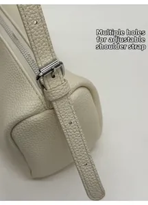 Macro detail of adjustable leather shoulder strap with silver buckle on beige baguette bag