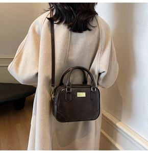 Macro detail of dark brown retro crossbody bag with golden metal buckle and leather texture