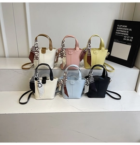 Detail of mini bucket bags in multiple colors featuring decorative silk-wrapped handles