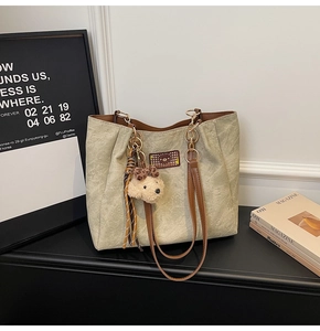 Close-up of light green tote bag with teddy bear embossing and leather straps