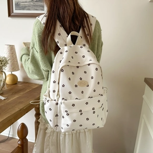 Detail view of cream canvas backpack with dark floral pattern on a female model