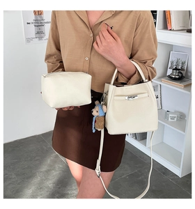 Detail of cream white leather bucket bag with silver hardware and a cute bear charm