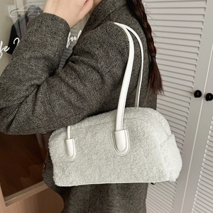 Detail of white plush pillow bag with leather handles and silver bottom protective studs