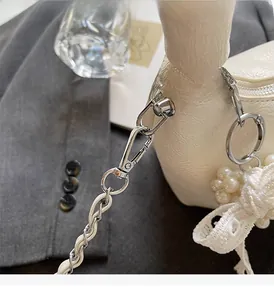 Détail de la chaîne argentée et du nœud perlé sur le sac à main en cuir plissé