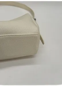 Macro view of widened base and lychee grain texture on white leather shoulder bag