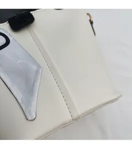 Detail of white leather tote with decorative silk scarf and black fashion brand tag