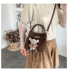 Detail of dark brown lychee textured bucket bag with silver lock and bear charm