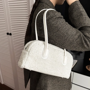 Close-up of white plush texture and smooth leather handle on a minimalist handbag