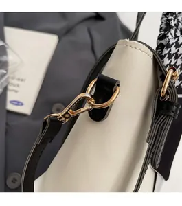 Detail of off-white leather bucket bag with gold hardware and houndstooth silk scarf