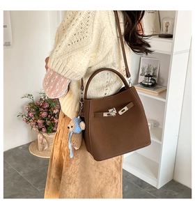Detail of dark brown leather bucket bag with silver buckle and cute bear charm