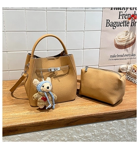 Detail of ginger leather bucket bag with matching pouch and bear charm on wood surface