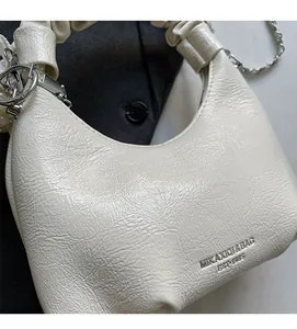 Détail du sac en cuir plissé blanc avec bandoulière chaîne argentée et gaufrage logo