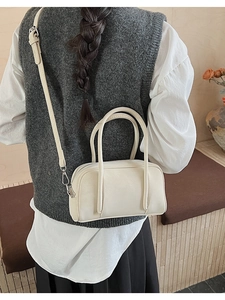 Cream leather bowling bag styled as a crossbody on a model in a minimalist home setting